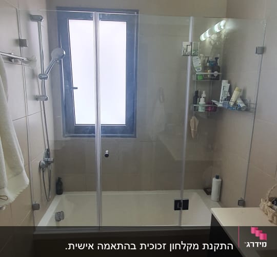 מקלחת עם דלת זכוכית, מדף עם מוצרי טיפוח